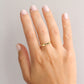 Hand wearing a thin gold signet ring with a lavender engraving